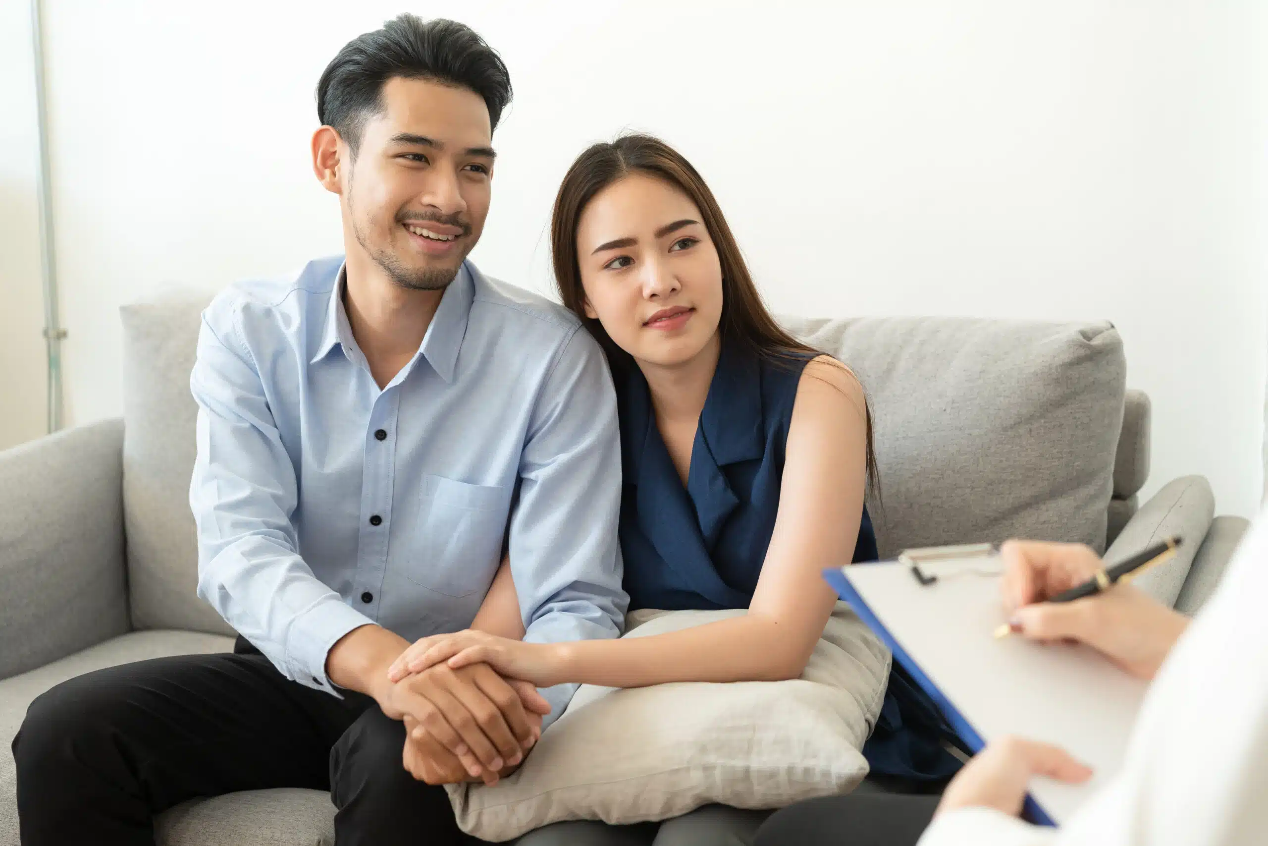 Couple sitting on a couch during a therapy session, holding hands and engaging with a
